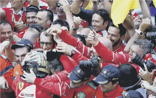  ??  ?? 2 Ferrari team members mob Sebastian Vettel as he celebrates his Monaco win.