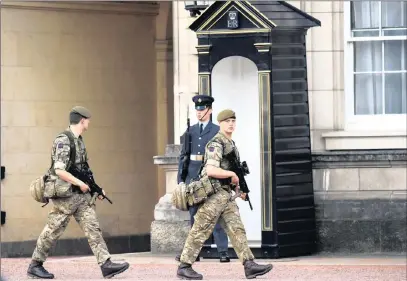  ?? PICTURE: REUTERS ?? Soldiers walk past a guardsman in the grounds of Buckingham Palace in London. Armed troops have been deployed at vital locations after the official threat level was raised to its highest point following a suicide bombing in Manchester that killed 22...
