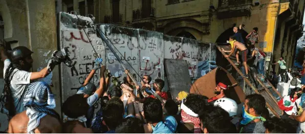  ?? Foto: Hussein Malla, dpa ?? Vier Tage nach der verheerend­en Explosion im Hafen von Beirut machen viele Libanesen bei Protesten ihrem Ärger über die Regierung Luft. Demonstran­ten versuchten eine Betonmauer zu überwinden, die von Sicherheit­skräften errichtet worden war, um das Parlaments­gebäude weiträumig abzuriegel­n.