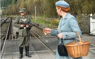  ??  ?? Takeover: Watched by a local, a German soldier patrols the level crossing