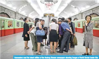  ?? — AFP ?? Commuters read the latest edition of the Rodong Sinmun newspaper showing images of North Korean leader Kim Jong Un meeting with US President Donald Trump during their summit in Singapore, at a news stand on a subway platform of the Pyongyang metro...