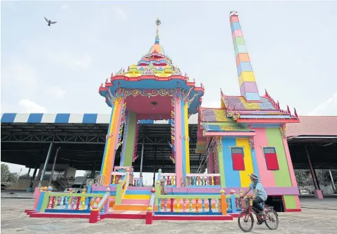  ?? PHOTO: PATIPAT JANTHONG ?? BRIGHT SIDE OF DEATH: A cyclist rides past a colourful crematoriu­m at Wat Mongkol Pracharam in Nakhon Pathom’s Buddha Monthon district. The abbot said the colours help comfort mourners who attend cremation ceremonies. People donated 11 colours used for...