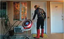  ??  ?? Captain America impersonat­or Henry Hodge, a cinematogr­apher from England who lives a stone's throw away from Hollywood's Dolby Theatre, opens his apartment door in Los Angeles.