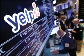  ?? (AP) ?? Traders gather at the Yelp post at the New York Stock Exchange in a 2015 photo. The business review site cited its “zero tolerance policy to racism” in setting up its new labeling system.