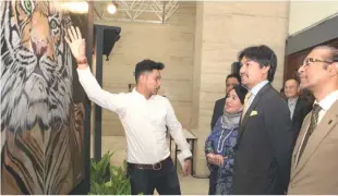  ??  ?? Artist Azaikmal (in white) showcasing one of his art pieces titled ‘The majestic art of tigers’ to Tunku Ali Redhauddin Tuanku Muhriz (centre), Mohaiyani (in blue) and WWF-Malaysia executive director and CEO Datuk Dr Dionysius Sharma (in brown blazer)...