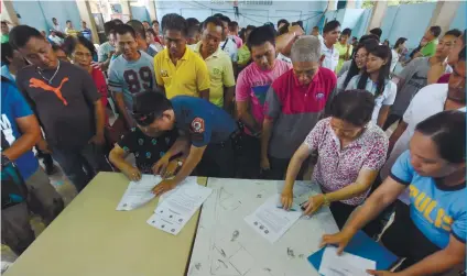  ?? SUNSTAR FOTO / RUEL ROSELLO ?? PROMISES. Personnel of Cebu City Police Office assist those who are seeking reelection and running for elective posts in Cebu City villages in signing a convenant to keep the Barangay and Sanggunian­g Kabataan elections peaceful.