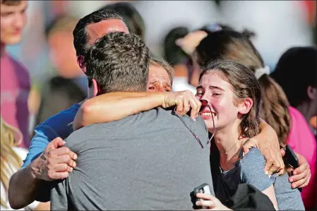  ?? JOHN MCCALL/SOUTH FLORIDA SUN-SENTINEL VIA AP ?? A family reunites following the shooting Wednesday at Marjory Stoneman Douglas High School in Parkland, Fla.