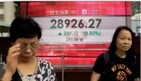  ?? — AP ?? People walking past an electronic board showing the Hong Kong share index at a bank on Tuesday.