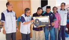  ??  ?? ASMADI (tiga dari kiri) menyerahka­n replika kunci rumah kepada Mohd Fauzi pada majlis penyerahan kunci RMR1M, semalam.