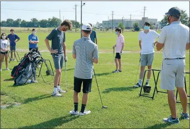  ?? (NWA Democrat-Gazette/Graham Thomas) ?? Siloam Springs golf coach Michael Robertson (right) speaks to his golfers before they practiced hitting at the driving range at Siloam Springs Rodeo Grounds.