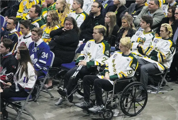  ??  ?? Crash survivors Graysen Cameron, right, and Derek Patter watch a tribute during the funeral of Humboldt player Evan Thomas in Saskatoon Monday.