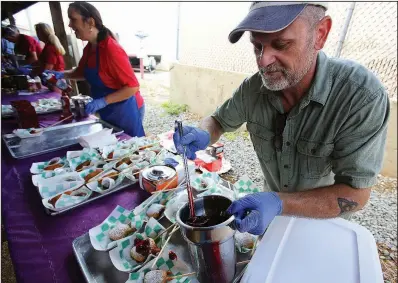  ?? Arkansas Democrat-Gazette/THOMAS METTHE ?? Morgan Curtis of Pat’s Kitchen puts cherry pie filling on fried dessert being sampled Wednesday during a State Fair media preview event at the State Fairground­s.