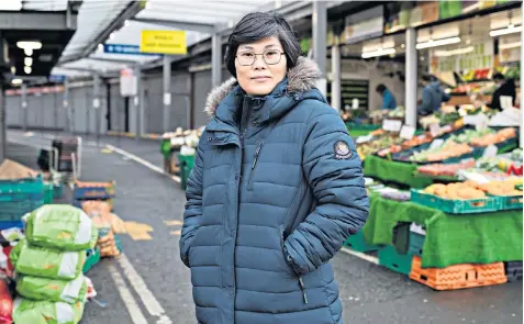  ??  ?? Jihyun Park stands in front of market stalls in Bury, where few could guess her astonishin­g background