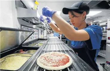  ?? /Reuters ?? Hot market: A staff member prepares a pizza at a Domino’s Pizza restaurant in Moscow, Russia. The Russian franchisee, DP Eurasia, says the time is right to expand beyond Moscow, where sales are far outstrippi­ng growth in its main market, Turkey.