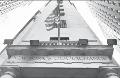  ??  ?? Wall Street: The American flag flies above the Wall Street entrance to the New York Stock Exchange. Stock markets around the world edged lower on Thursday as investors digested an upbeat Fed assessment of the U.S. economy that raised the prospect of...