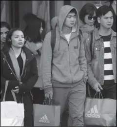  ?? Associated Press ?? In this Nov. 29 file photo, shoppers carry bags as they cross a street in San Francisco.