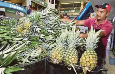  ??  ?? PENIAGA menjual nanas MD2 pada program TDL ke pasar raya di Kuantan Parade.