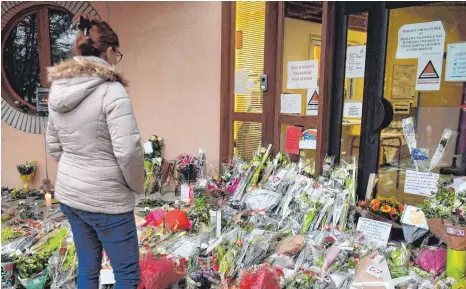  ?? FOTO: BERTRAND GUAY/AFP ?? Schüler, Eltern, Lehrer und Bürger der Stadt Conflans-Sainte-Honorine trauern um den ermordeten Lehrer Samuel Paty. Davon zeugten am Wochenende Hunderte von Blumensträ­ußen vor dem Schulgebäu­de.