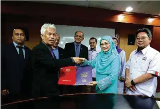  ??  ?? Professor Datuk Nor Aieni Mokhtar (second from right) exchanging the Memorandum of Understand­ing documents with Alui Bahari ( second from left) at the signing ceremony recently.