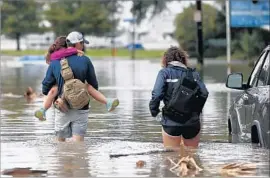  ?? Gerald Herbert Associated Press ?? DON NOEL braves a f looded roadway in New Orleans with daughter Alexis, 8, and wife Lauren. The northern Gulf Coast was bracing for more flooding.