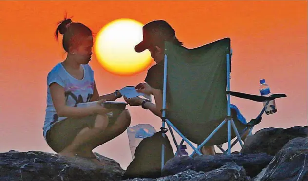  ?? Kamal Kassim / Gulf Today ?? The couple is relaxing in the twilight by a beach in Ajman.