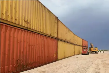  ?? Arizona Governor’s Office ?? Workers near Yuma, Ariz., stack shipping containers Friday as part of a state initiative to fill gaps in the border wall with Mexico. Republican Gov. Doug Ducey plans to fill three gaps totaling 3,000 feet.