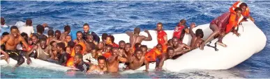 ??  ?? Risking their lives: Migrants trying to reach Italy await rescue from a sinking boat