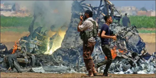  ??  ?? Ablaze: Men inspect wreckage of a Russian helicopter shot down yesterday in the north of Syria’s rebel-held Idlib province