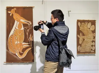  ??  ?? A visitor takes a picture of “Mimih Hunting” by Aboriginal artist Dick Nguleingul­ei Murrumurru at the Natural History Museum yesterday. — Jiang Xiaowei