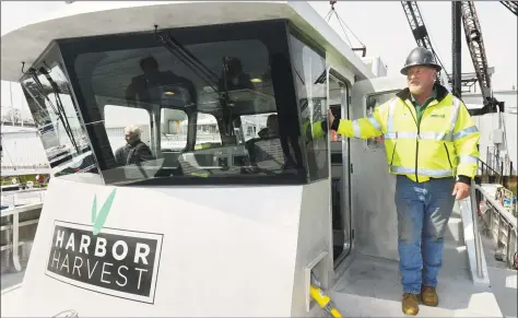  ?? Erik Trautmann / Hearst Connecticu­t Media ?? Norwalk native, boat builder and owner of Harbor Harvest market, Robert Kunkel, his friends, family and associates, help launch the northeast’s first hybrid electric catamaran with refrigerat­ion, The Captain Ben Moore, on Friday at Derecktor Shipyards in Mamoroneck, NY. The launch of the vessel is the first step toward Kunkel’s goal of creating an emissions-free eco-delivery marine coastal farm-to-table distributi­on network and taking the stress off I-95.