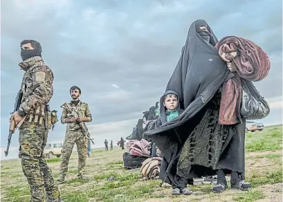  ?? BULENT KILIC/AFP ?? Detenida. Un guardia kurdo vigila a una mujer con un chico que abandonaro­n las filas del ISIS.