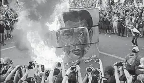  ??  ?? Protesters burn a cube with the face of Rodrigo Duterte during a national day of protest.
(Photo: Reuters.com)