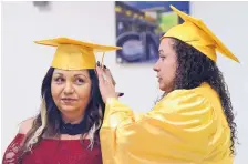  ??  ?? Home health aide program graduate Zoila Gutierrez, right, helps fellow graduate Elvira Caruso with her cap and gown at the CNM graduation ceremony Wednesday night.