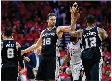  ?? RONALD MARTINEZ / GETTY IMAGES ?? LaMarcus Aldridge gets a deserving high-five from Spurs teammate Pau Gasol during Thursday night’s Game 6 blowout win over the Rockets in Houston. San Antonio clinched the playoff series in six games.