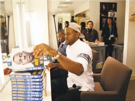  ?? Grace Li / The Chronicle ?? Andre Iguodala signs copies of “The Sixth Man” with cowriter Carvell Wallace at the Jewish Community Center of San Francisco.
