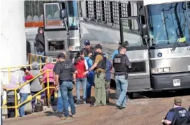  ?? AP PHOTO/ROGELIO V. SOLIS ?? Handcuffed female workers are escorted onto a bus Wednesday for transporta­tion to a processing center following a raid by U.S. immigratio­n officials at a Koch Foods Inc. plant in Morton, Miss.