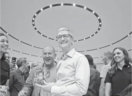  ?? JUSTIN SULLIVAN/GETTY IMAGES ?? Apple CEO Tim Cook, center, shows off the iPhone X in September. Apple has scheduled a “special event” at a high school in Chicago this week, but the company has not said what it might announce there.