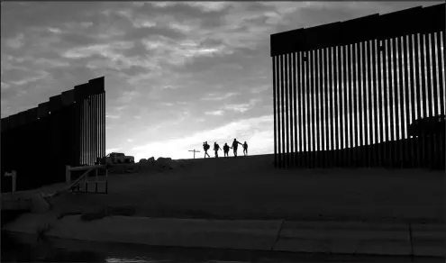  ?? EUGENE GARCIA / ASSOCIATED PRESS ?? A pair of migrant families from Brazil pass through a gap in the border wall to reach the United States after crossing from Mexico to Yuma, Ariz., to seek asylum.