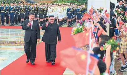  ?? Shen hong/AFP ?? Un grupo de chicos saluda a Xi y Kim con banderas chinas y norcoreana­s