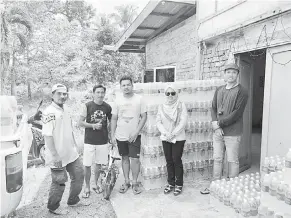  ??  ?? HANTAR: Zulhaidah (empat kiri) bersama rombongan dan penduduk kampung memunggah karton-karton air minuman untuk diedar ke setiap rumah.