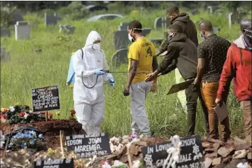  ?? Tsvangiray­i Mukwazhi Associated Press ?? A HEALTH WORKER disinfects family members during the burial of a person who died of COVID-19 last month in Harare, Zimbabwe. A virus variant dominant in South Africa is challengin­g vaccinatio­n efforts.