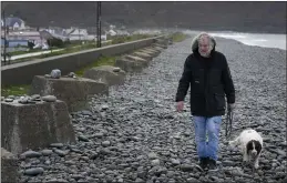  ?? KIRSTY WIGGLESWOR­TH — THE ASSOCIATED PRESS ?? Stuart Eves walks along the beach with his dog Lucy in Fairbourne village in Gwynedd in Wales on Wednesday.