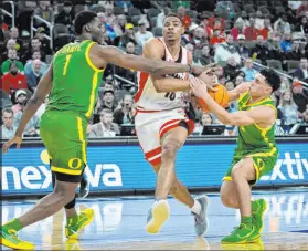  ?? John Locher The Associated Press ?? Arizona’s Keshad Johnson tries to drive through Oregon’s N’faly Dante (1) and Jackson Shelstad on Friday at T-mobile Arena.