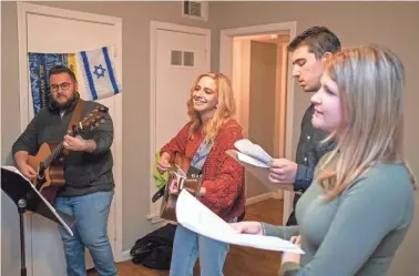  ?? BRANDON DAHLBERG/FOR THE COMMERCIAL APPEAL ?? Michael Sarna, Carly Abramson, Max Abraham, and Paige Mandelman lead services during an Undergroun­d Shabbat on Jan. 24 in Memphis.