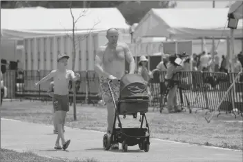  ?? MARCO UGARTE/AP ?? A UKRAINIAN REFUGEE walks with his children at a camp in Utopia Park, Iztapalapa, Mexico City on Monday.