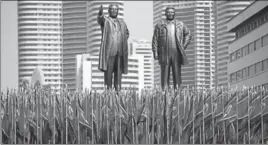  ?? REUTERS ?? People carry flags in front of statues of North Korea founder Kim Il Sung (left) and late leader Kim Jong Il during a military parade marking the 105th birth anniversar­y of Kim Il Sung in Pyongyang.