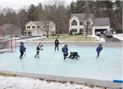  ??  ?? Children play hockey on a backyard rink built with an Iron Sleek rink kit in Wilton, New York.