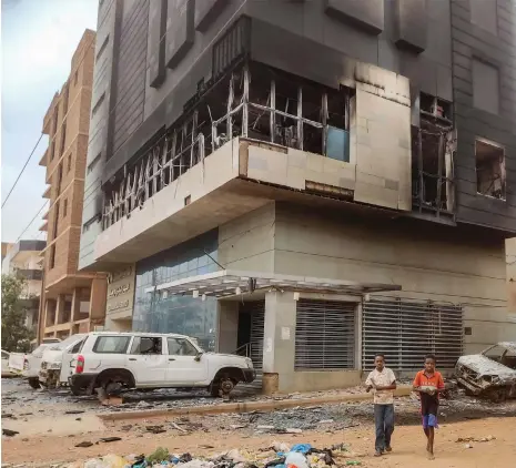  ?? AFP ?? Children walk past the burnt-out headquarte­rs of Sudan’s Central Bureau of Statistics in the south of Khartoum