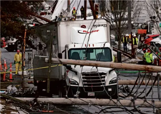  ?? PHOTOS BY DAVID L RYAN/GLOBE STAFF ?? Seven utility poles fell after a tractor-trailer snagged a power line on Montvale Avenue in Stoneham Wednesday.