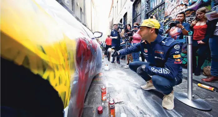  ??  ?? De Australisc­he coureur Daniel Ricciardo beschilder­t een auto op de persdag van zijn team voorafgaan­d aan de Grand Prix in Melbourne.